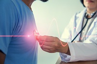 Doctor holding a stethoscope to a patient's heart