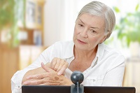 woman showing skin spot to webcam on laptop