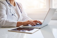 female physician typing on a laptop