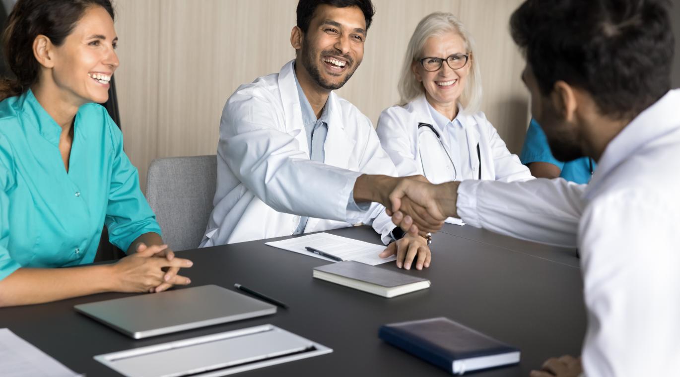 International clinic chief medical person shake hand of young male doctor congratulate new member with getting job starting career.