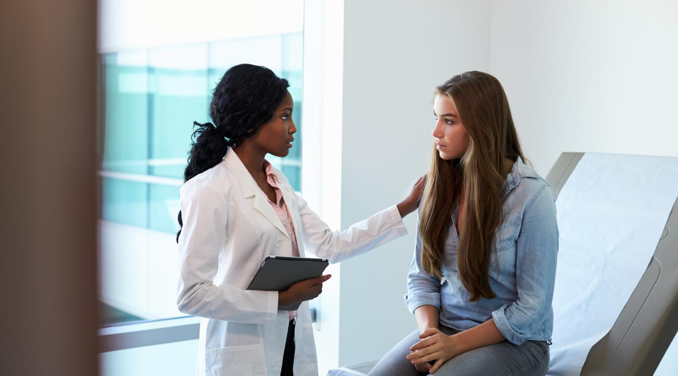 physician comforting a patient with a hand on her shoulder