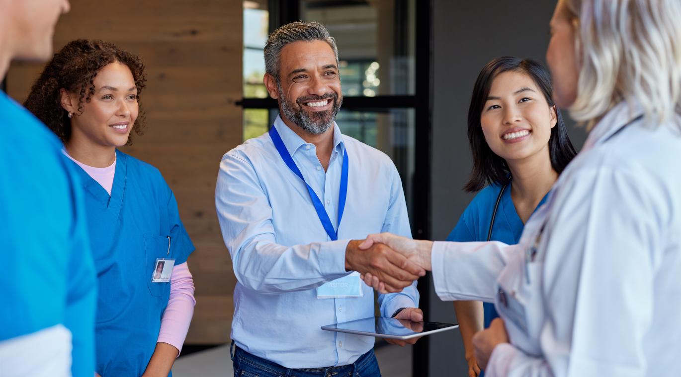 Mature woman doctor shaking hands with pharmaceutical representative at hospital