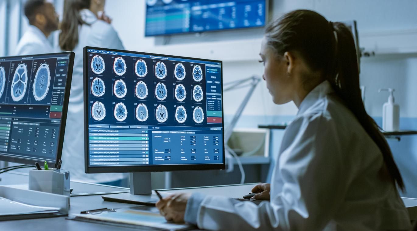 physician looking at brain scans on a laptop screen