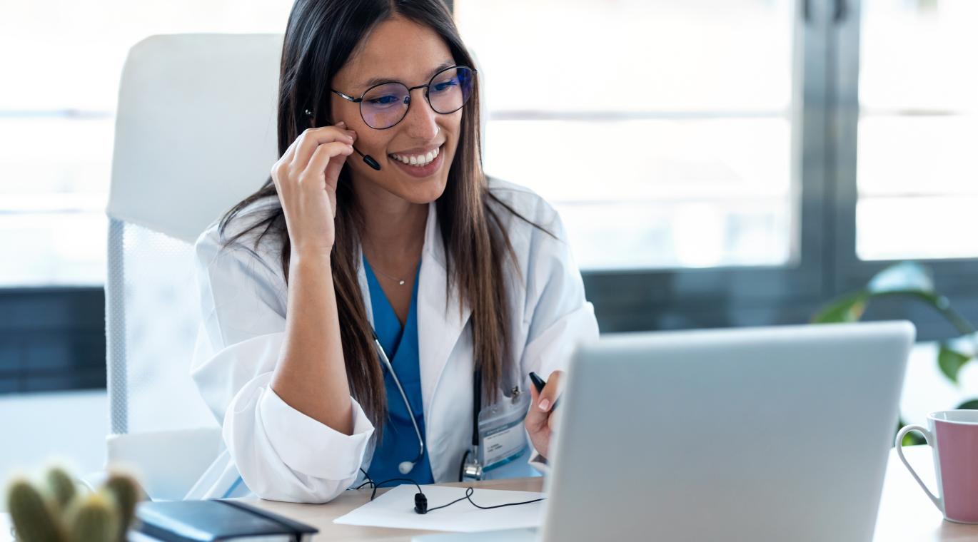 female physician smiling staring at laptop screen