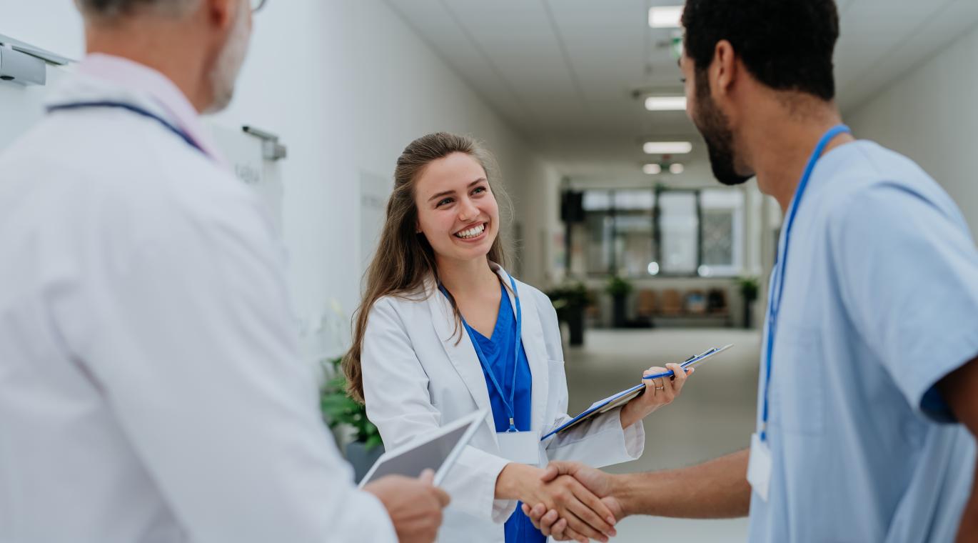 Three doctors, one male and female physician shaking hands