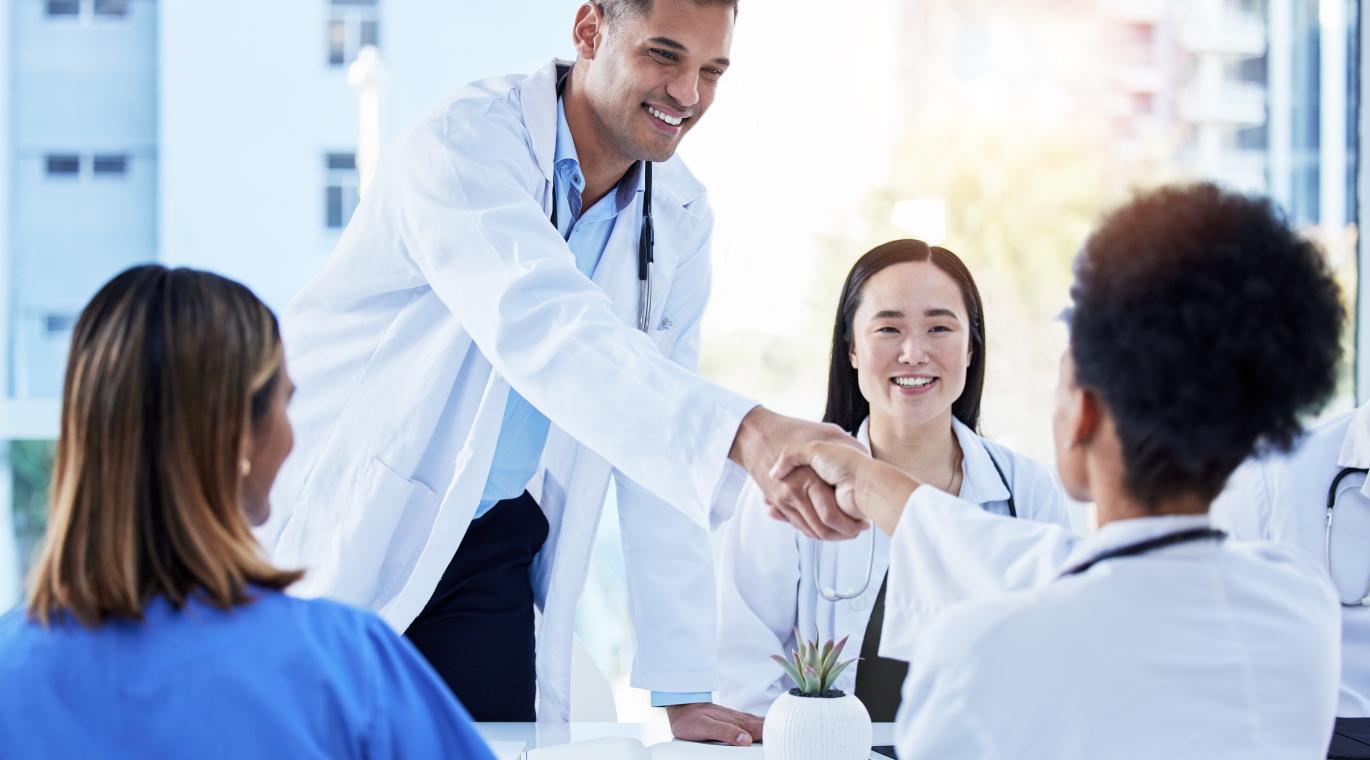 Happy healthcare employees shaking hands in hospital