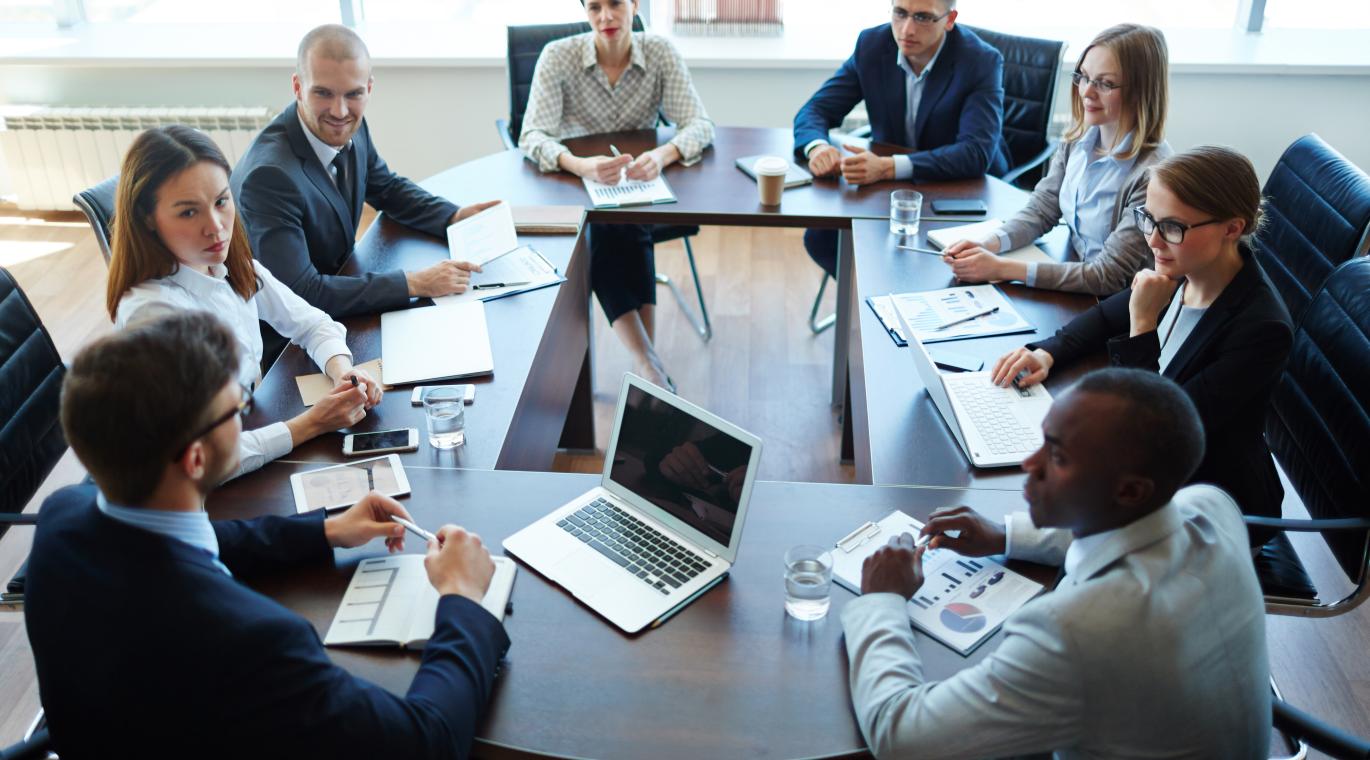 group of employees sitting around a circle table in a boardroom