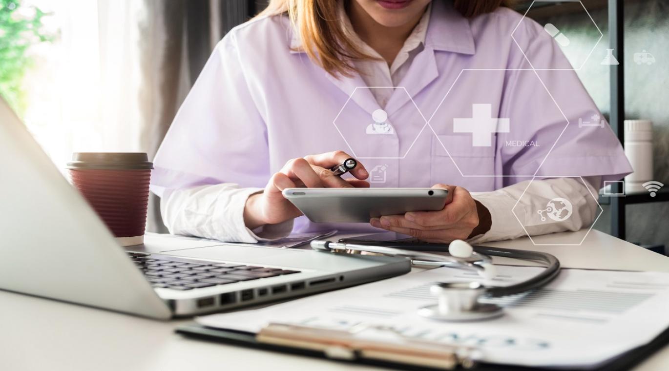 female physician using a tablet with a stethoscope on the table