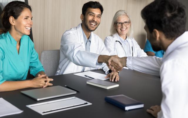 International clinic chief medical person shake hand of young male doctor congratulate new member with getting job starting career. 