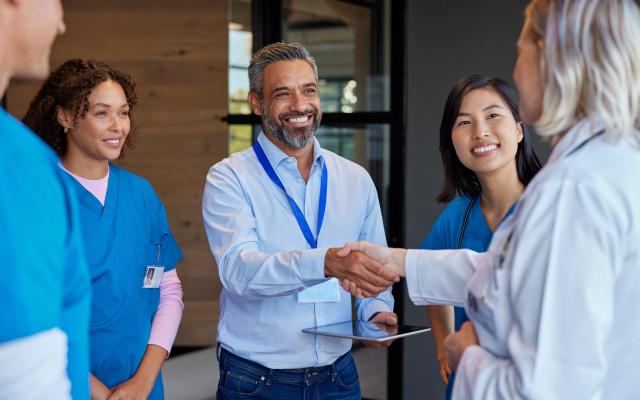 Mature woman doctor shaking hands with pharmaceutical representative at hospital