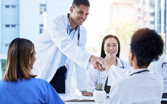 Happy healthcare employees shaking hands in hospital