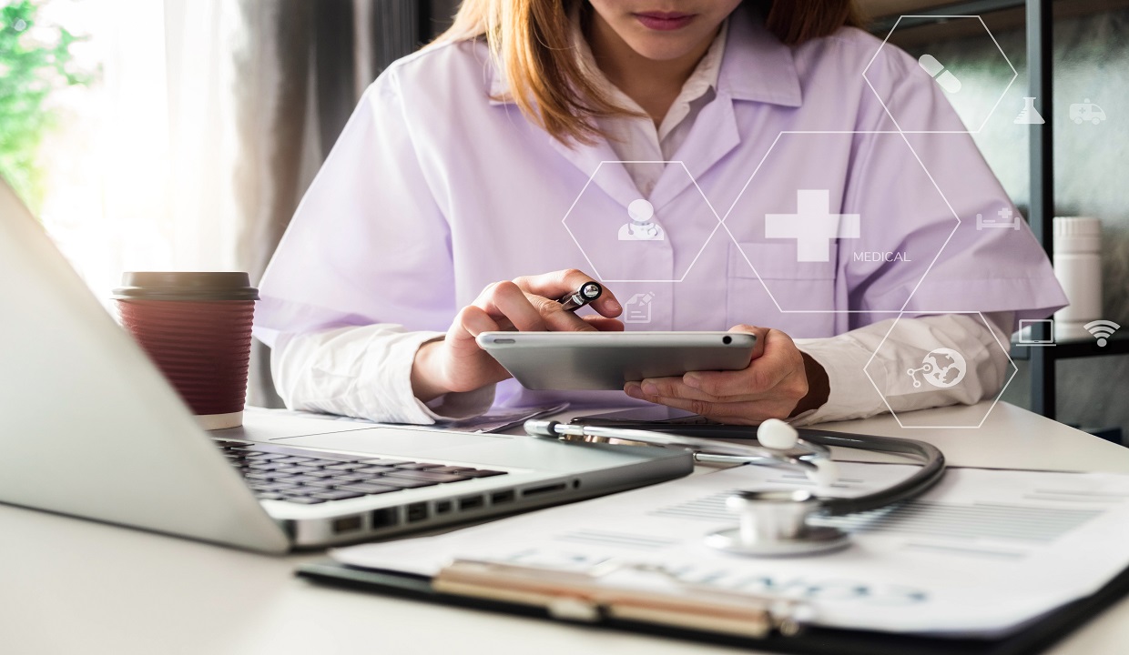 female physician using a tablet with a stethoscope on the table
